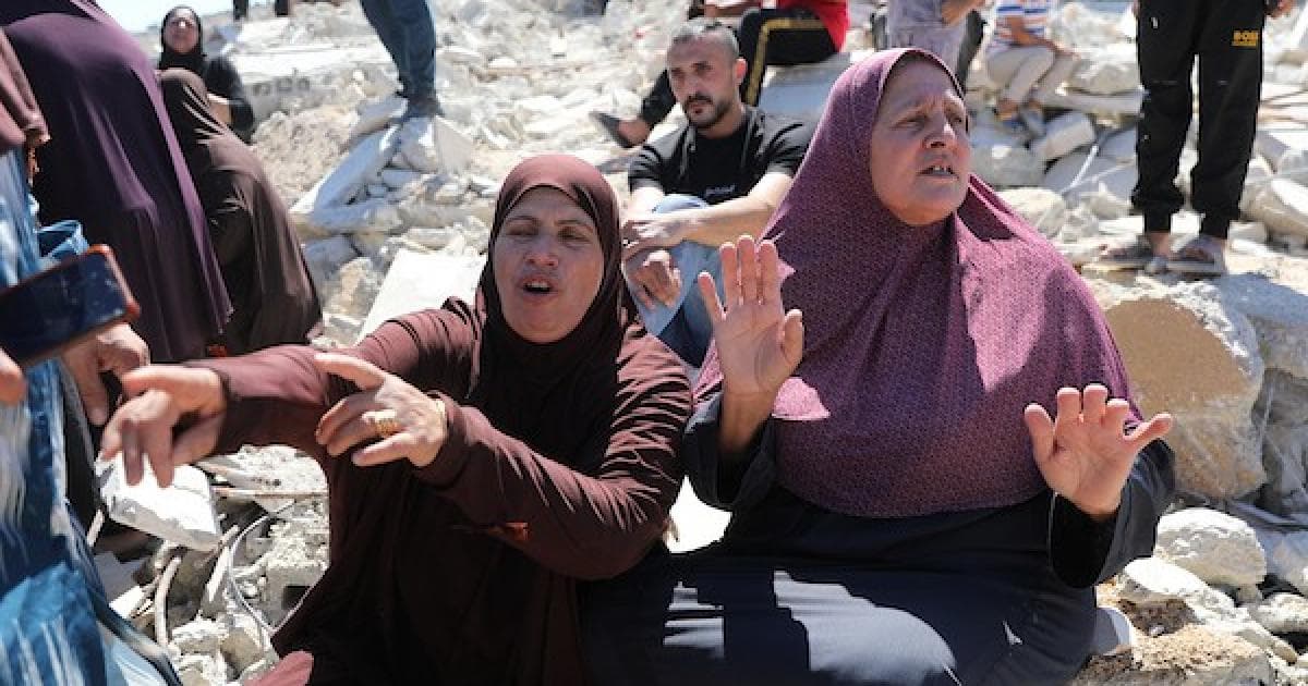 فلسطينيون يجلسون على أنقاض منزل مدمر في بيت عوا
