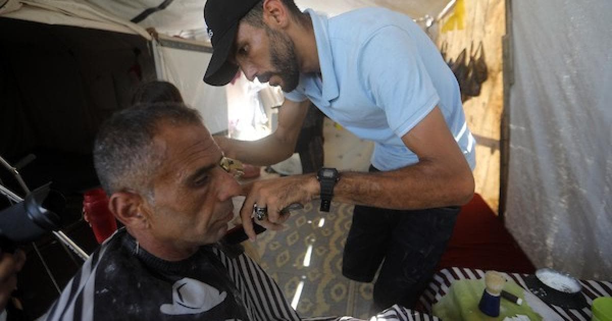فلسطيني حلاق يستمر في العمل بعد فقدان ساقه في غزة