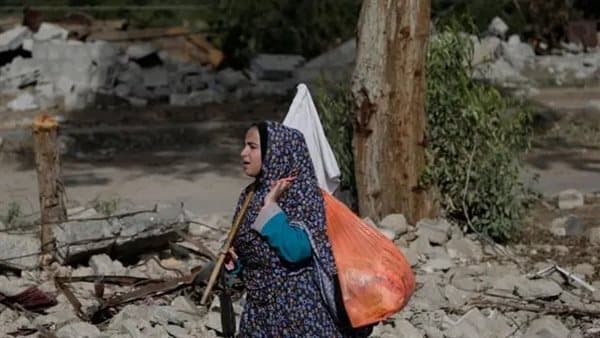 Palestinian woman bears Gaza amidst tents and rubble
